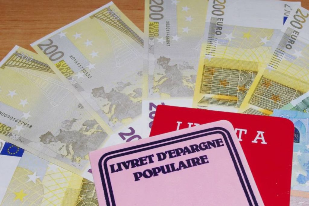Une pile de billets en euros et un passeport sur une table.